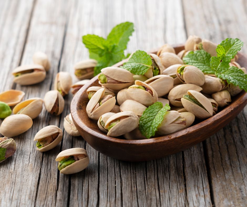 Pistachios with shells in a wooden bowl with mint leaves